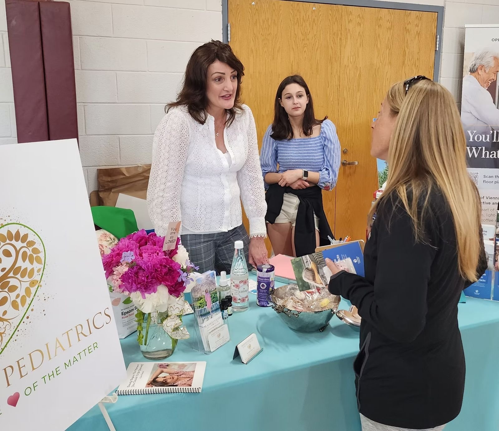 An exhibitor table with flowers and handouts